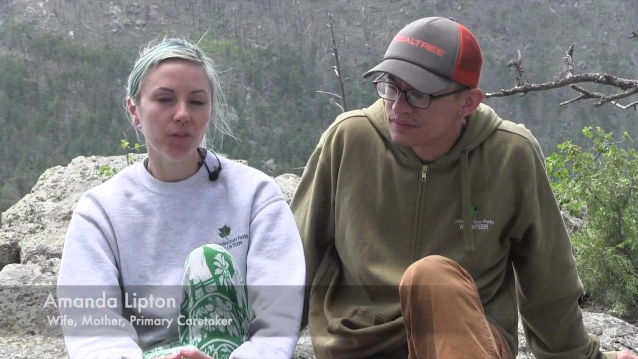 Amanda Lipton, seated outdoors beside Tri, identified on screen as wife, mother and primary caretaker.