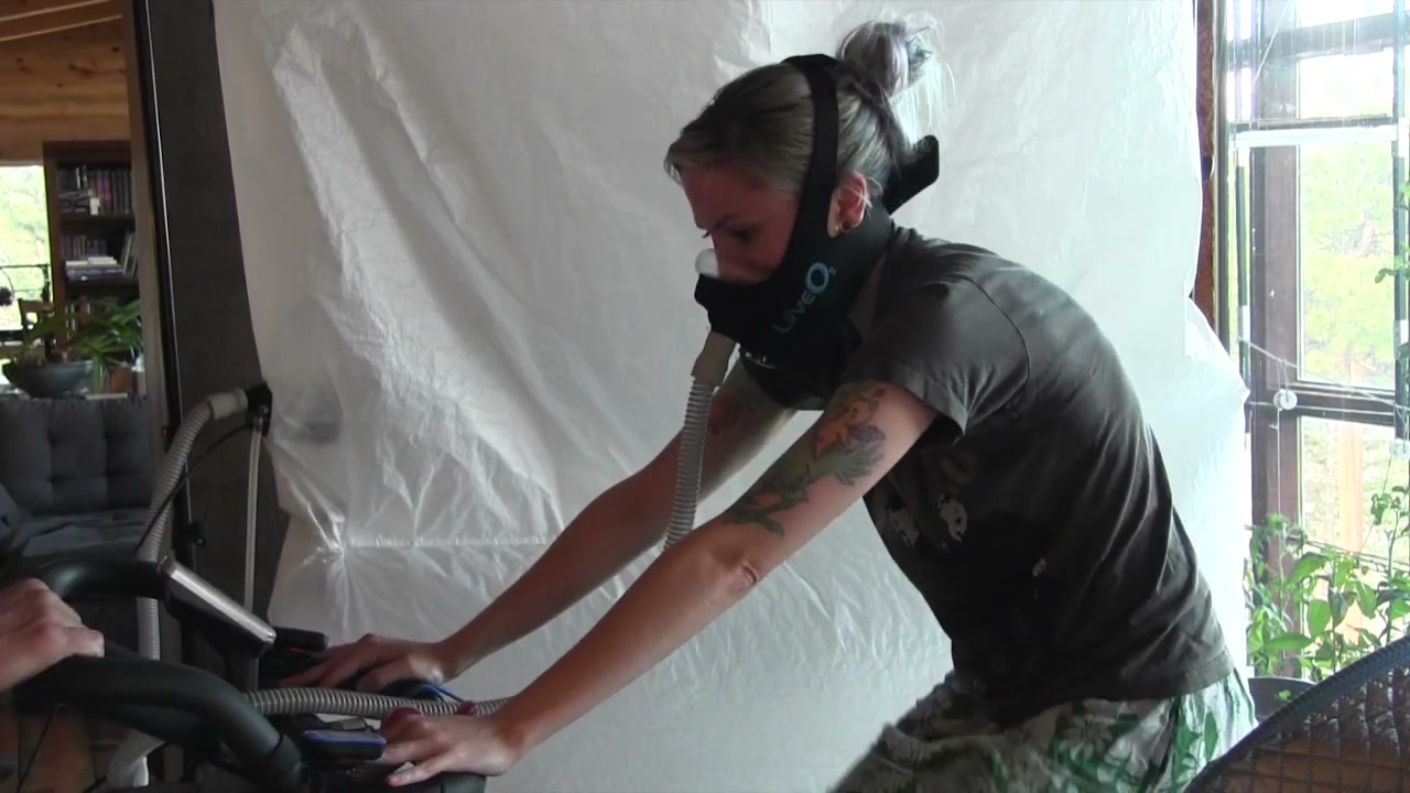 Amanda Lipton on the same stationary bike wearing the oxygen mask.